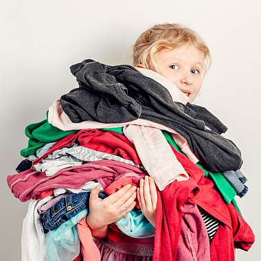 Ein Kind trÃ¤gt seine Kleider auf dem Arm. Besser mit einer Garderobenversicherung.